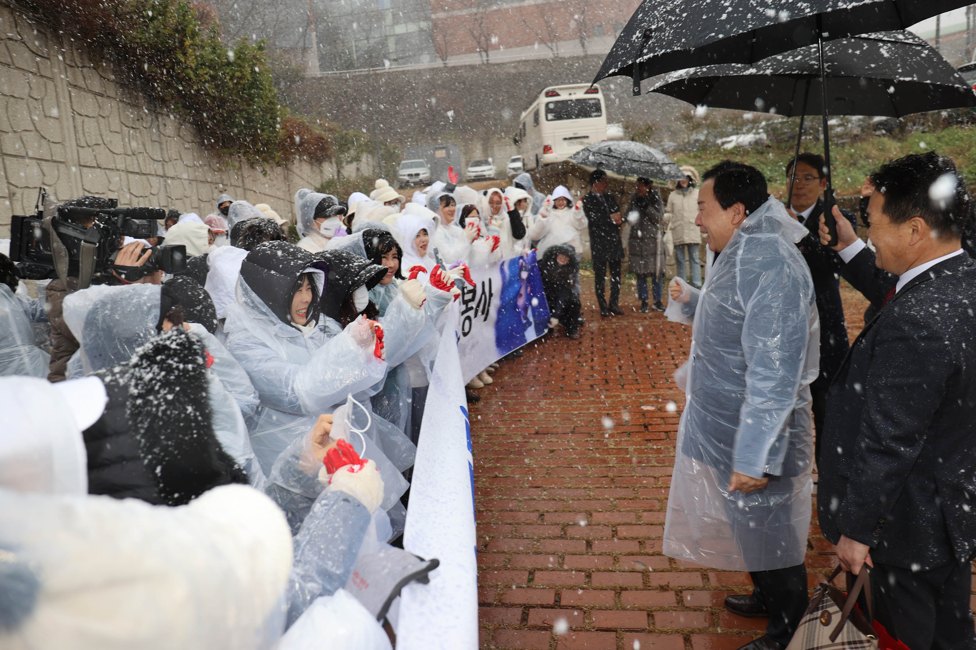 눈오는날 플랜카드를 들며 박홍률 목포시장 앞에있는 봉사단들이 측면에서 찍힌사진