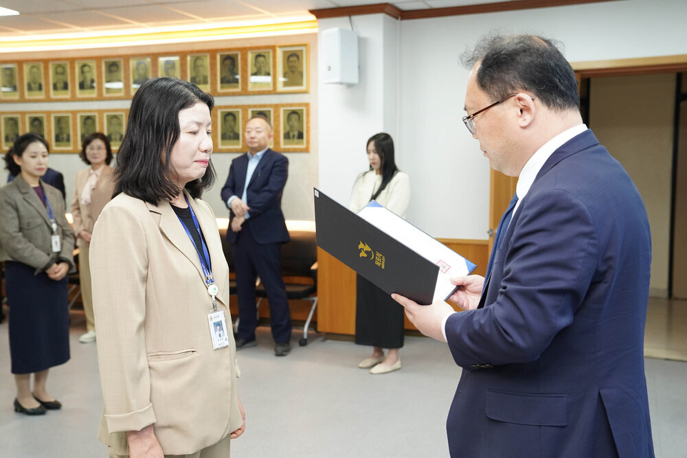 수시인사 임용장 수여식에서 정장을 입은 남성이 베이지색 정장을 입은 여성 직원에게 임용장을 전달하는 모습
