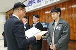 11월 정례조회로 정장을 입고 안경을 쓴 남성이 짧은 파마머리에 파스텔톤 카키색 상의에 김세훈 수상자에게 상장을 수여 하고 있다.